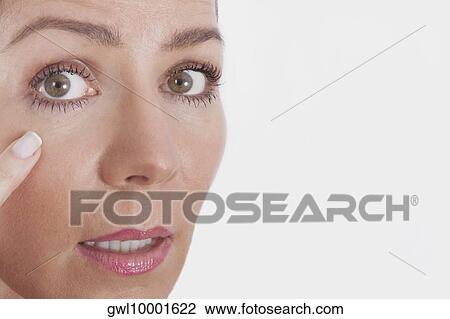 Stock Image - Close-up of a woman examining her face. Fotosearch