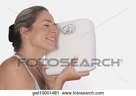 Close-up of a woman holding a bathroom scale and smiling View Large Photo Image Stock Image - Close-up of a woman holding a bathroom scale and smiling. Fotosearch