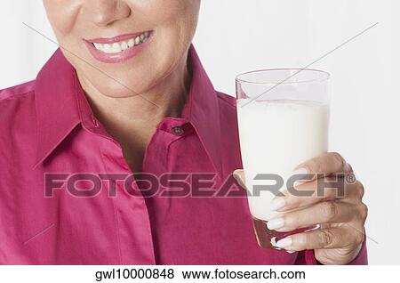 Close-up of a woman holding a glass of milk View Large Photo Image Stock Photo - Close-up of a woman holding a glass of milk. Fotosearch
