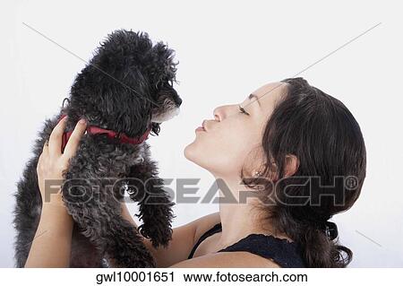 Stock Image - Close-up of a woman kissing her poodle. Fotosearch