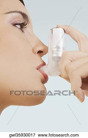Stock Photo - Close-up of a woman using an inhaler. Fotosearch