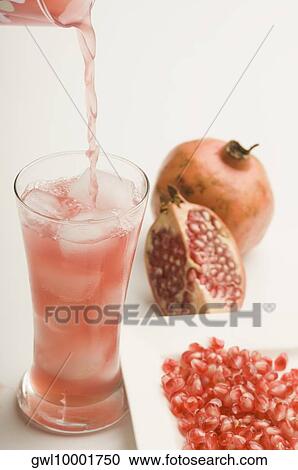 Stock Image - Close-up of pomegranate with a glass of pomegranate juice. Fotosearch