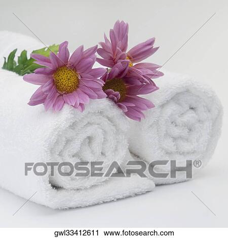 Stock Image - Close-up of rolled up towels with flowers. Fotosearch