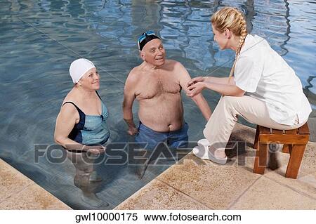 Couple enjoying in a swimming pool with a health worker at poolside View Large Photo Image Stock Photography - Couple enjoying in a swimming pool with a health worker at poolside. Fotosearch