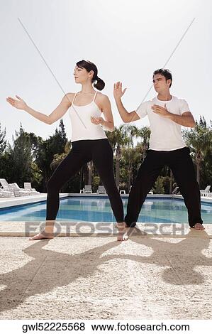 Couple exercising at the poolside View Large Photo Image Stock Photo - Couple exercising at the poolside. Fotosearch