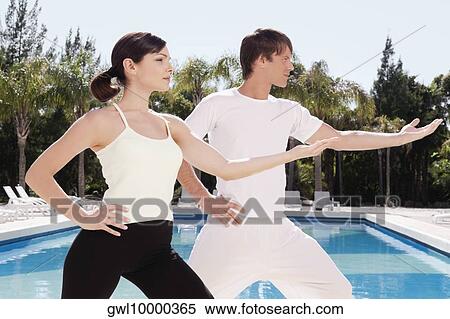 Couple exercising at the poolside View Large Photo Image Stock Photography - Couple exercising at the poolside. Fotosearch