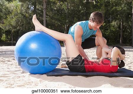 Couple exercising with a fitness ball on the beach View Large Photo Image Stock Image - Couple exercising with a fitness ball on the beach. Fotosearch