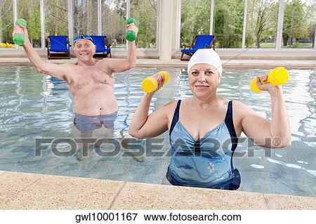 Couple exercising with dumbbells in a swimming pool View Large Photo Image Stock Photo - Couple exercising with dumbbells in a swimming pool. Fotosearch