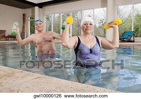 Couple exercising with dumbbells in a swimming pool View Large Photo Image Stock Photograph - Couple exercising with dumbbells in a swimming pool. Fotosearch