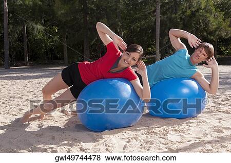 Couple exercising with fitness balls on the beach View Large Photo Image Stock Photo - Couple exercising with fitness balls on the beach. Fotosearch