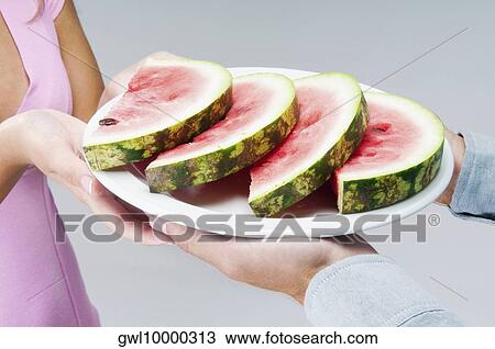Couple holding a plate of watermelon slices View Large Photo Image Stock Image - Couple holding a plate of watermelon slices. Fotosearch