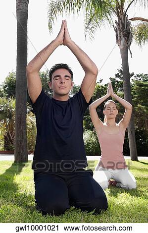 Couple practicing yoga in a park View Large Photo Image Stock Image - Couple practicing yoga in a park. Fotosearch