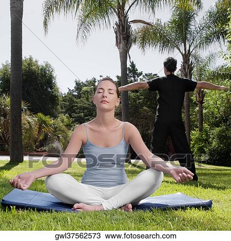 Couple practicing yoga in a park View Large Photo Image Stock Image - Couple practicing yoga in a park. Fotosearch