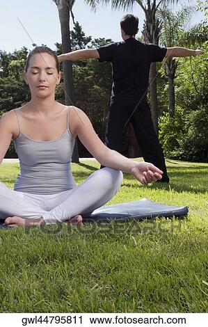 Couple practicing yoga in a park View Large Photo Image Stock Image - Couple practicing yoga in a park. Fotosearch