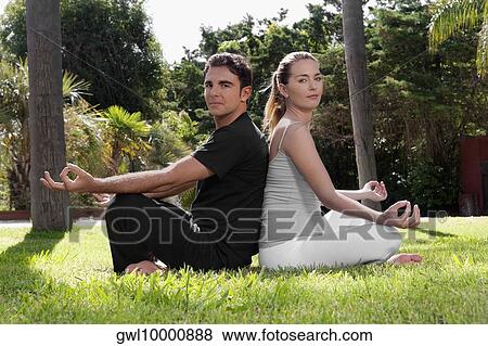 Couple practicing yoga in a park View Large Photo Image Stock Photo - Couple practicing yoga in a park. Fotosearch