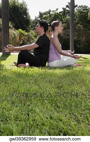 Couple practicing yoga in a park View Large Photo Image Stock Photo - Couple practicing yoga in a park. Fotosearch