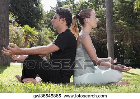 Stock Photography - Couple practicing yoga in a park. Fotosearch