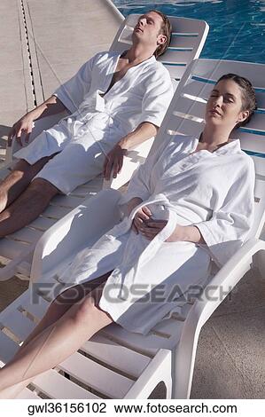 Couple resting on lounge chairs at the poolside View Large Photo Image Stock Image - Couple resting on lounge chairs at the poolside. Fotosearch