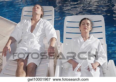Couple resting on lounge chairs at the poolside View Large Photo Image Stock Photo - Couple resting on lounge chairs at the poolside. Fotosearch
