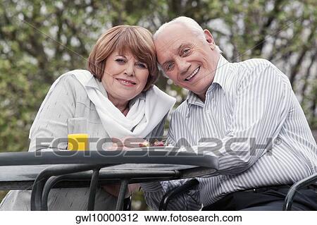 Stock Image - Couple sitting at a table and smiling. Fotosearch