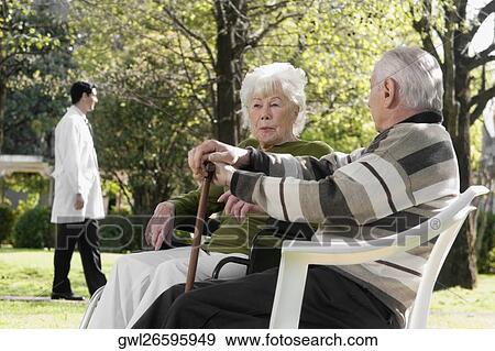 Couple sitting in a park View Large Photo Image Stock Photo - Couple sitting in a park. Fotosearch