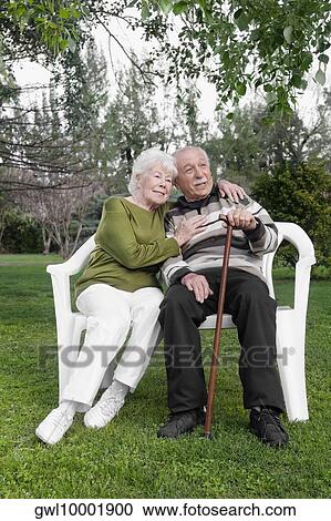 Stock Image - Couple sitting on chairs in a park. Fotosearch