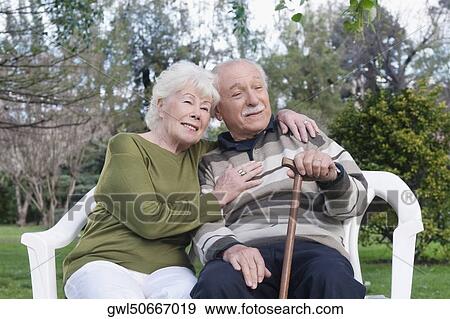 Couple sitting together in a park View Large Photo Image Stock Photo - Couple sitting together in a park. Fotosearch