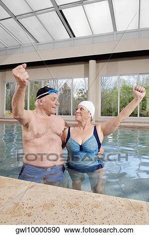 Couple smiling in a swimming pool with their hands raised View Large Photo Image Stock Image - Couple smiling in a swimming pool with their hands raised. Fotosearch