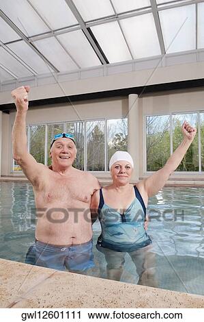 Couple smiling in a swimming pool with their hands raised View Large Photo Image Stock Image - Couple smiling in a swimming pool with their hands raised. Fotosearch