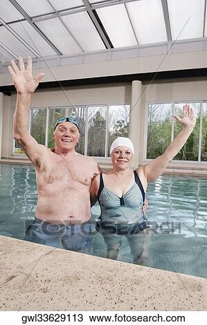 Couple smiling in a swimming pool with their hands raised View Large Photo Image Stock Image - Couple smiling in a swimming pool with their hands raised. Fotosearch