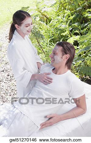 Stock Photograph - Couple smiling with facial masks on their faces. Fotosearch