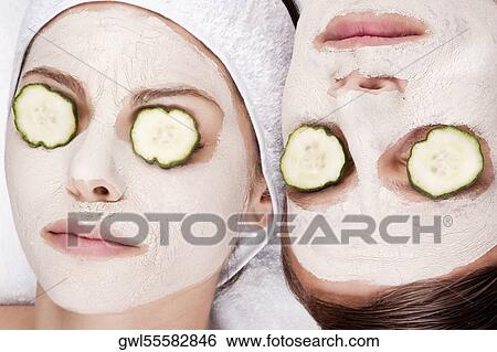Stock Photograph - Couple with face pack and cucumber slices on their eyes. Fotosearch