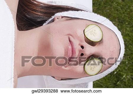 Stock Photo - Cucumber slices on a woman's eyes. Fotosearch