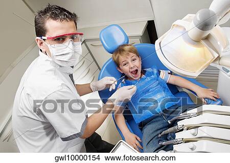 Dentist examining a boy's teeth View Large Photo Image Picture - Dentist examining a boy's teeth. Fotosearch