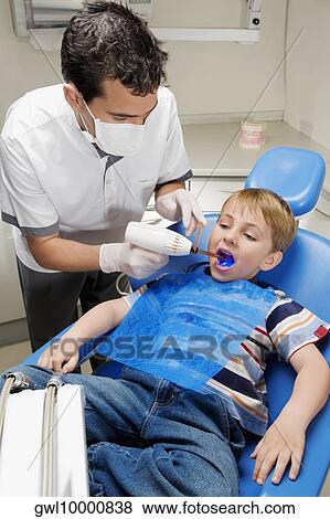 Dentist examining a boy's teeth View Large Photo Image Stock Photo - Dentist examining a boy's teeth. Fotosearch