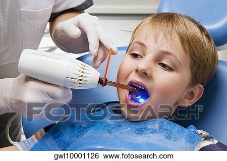 Dentist examining a boy's teeth View Large Photo Image Stock Photograph - Dentist examining a boy's teeth. Fotosearch