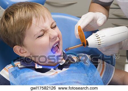 Dentist examining a boy's teeth View Large Photo Image Stock Photograph - Dentist examining a boy's teeth. Fotosearch