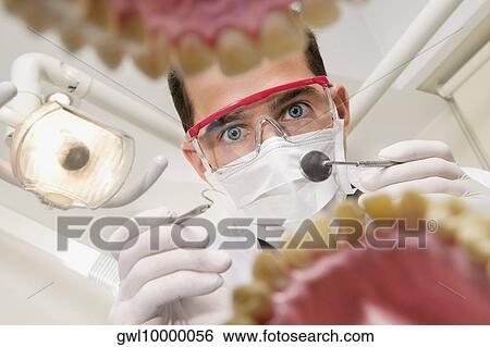 Stock Photograph - Dentist examining a set of dentures. Fotosearch
