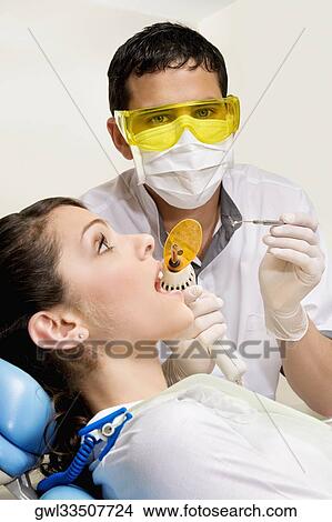 Dentist examining a woman's teeth View Large Photo Image Picture - Dentist examining a woman's teeth. Fotosearch
