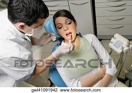 Dentist examining a woman's teeth View Large Photo Image Stock Image - Dentist examining a woman's teeth. Fotosearch