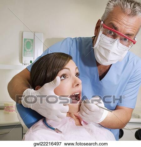 Dentist examining a woman's teeth View Large Photo Image Stock Photo - Dentist examining a woman's teeth. Fotosearch