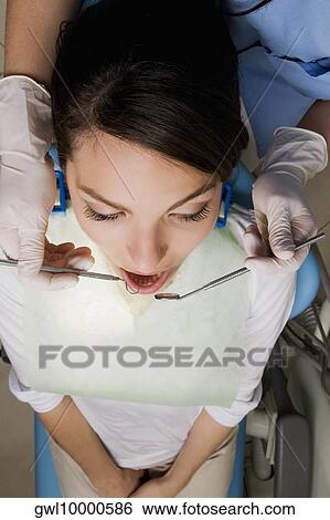 Dentist examining a woman's teeth View Large Photo Image Stock Photograph - Dentist examining a woman's teeth. Fotosearch