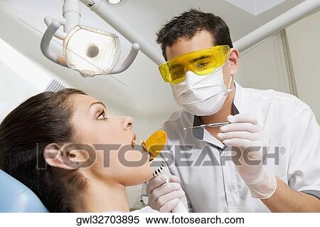 Dentist examining a woman's teeth View Large Photo Image Stock Photography - Dentist examining a woman's teeth. Fotosearch