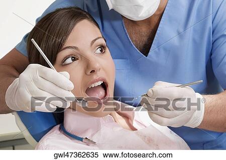 Dentist examining a woman's teeth View Large Photo Image Stock Photography - Dentist examining a woman's teeth. Fotosearch