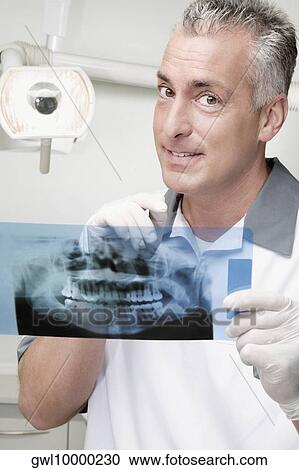 Stock Image - Dentist examining an X-Ray report. Fotosearch