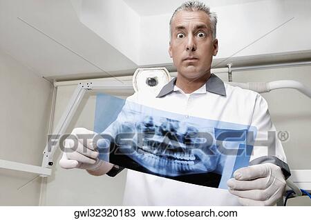 Dentist examining an X-Ray report View Large Photo Image Stock Image - Dentist examining an X-Ray report. Fotosearch