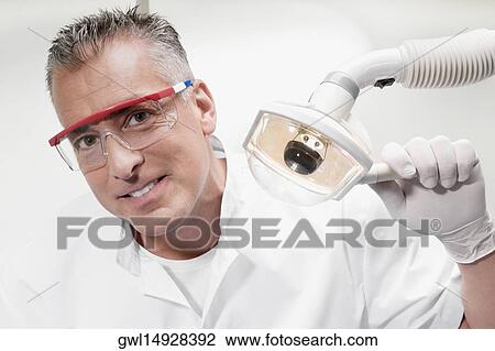 Dentist holding an examination lamp View Large Photo Image Stock Image - Dentist holding an examination lamp. Fotosearch