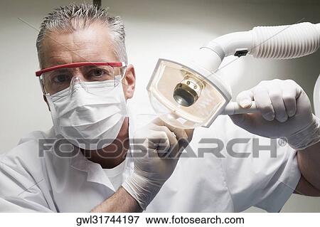 Dentist holding an examination lamp View Large Photo Image Stock Photo - Dentist holding an examination lamp. Fotosearch