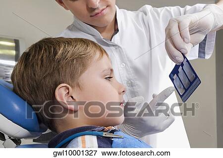 Stock Photo - Dentist showing an X-Ray report to a boy. Fotosearch