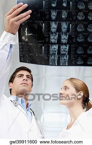 Stock Image - Doctor and a female nurse examining an x-ray report. Fotosearch